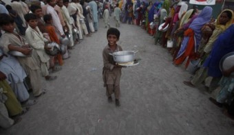 A flood victim child reacts after getting food handouts from a distribution point while taking refuge with his family in a r (1)
